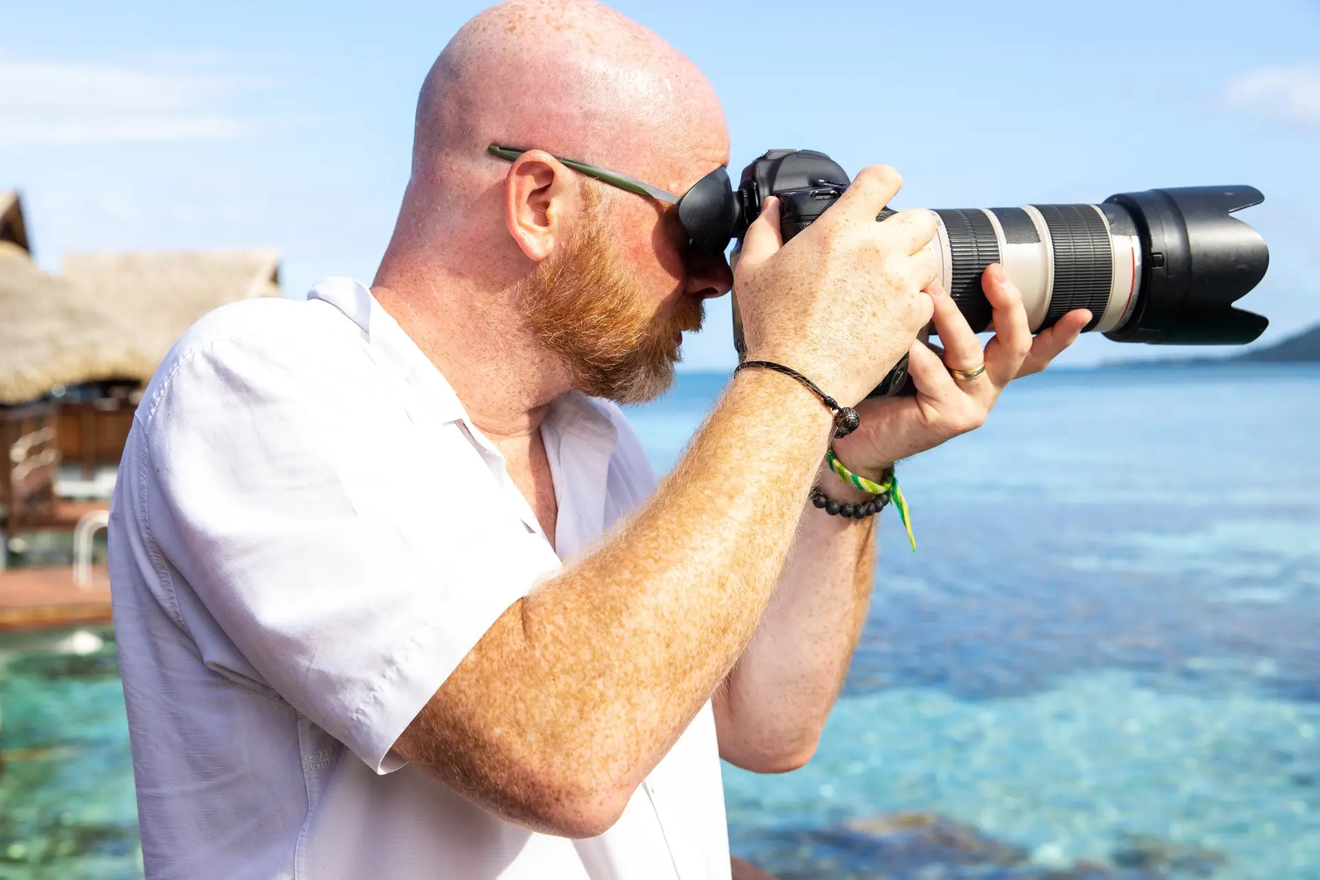 A man taking photos with a digital camera on the exterior of a tropical island while on holiday.