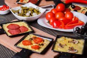 young woman is preparing a traditional Swiss cheese raclette