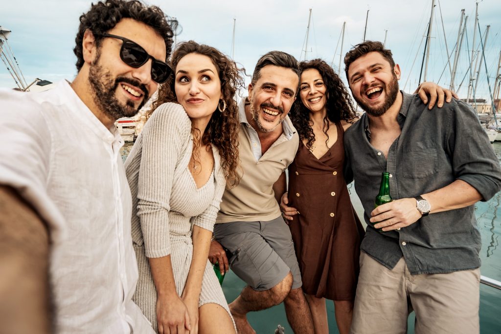 Amusing group selfie of happy friends enjoying a yacht party at a marina