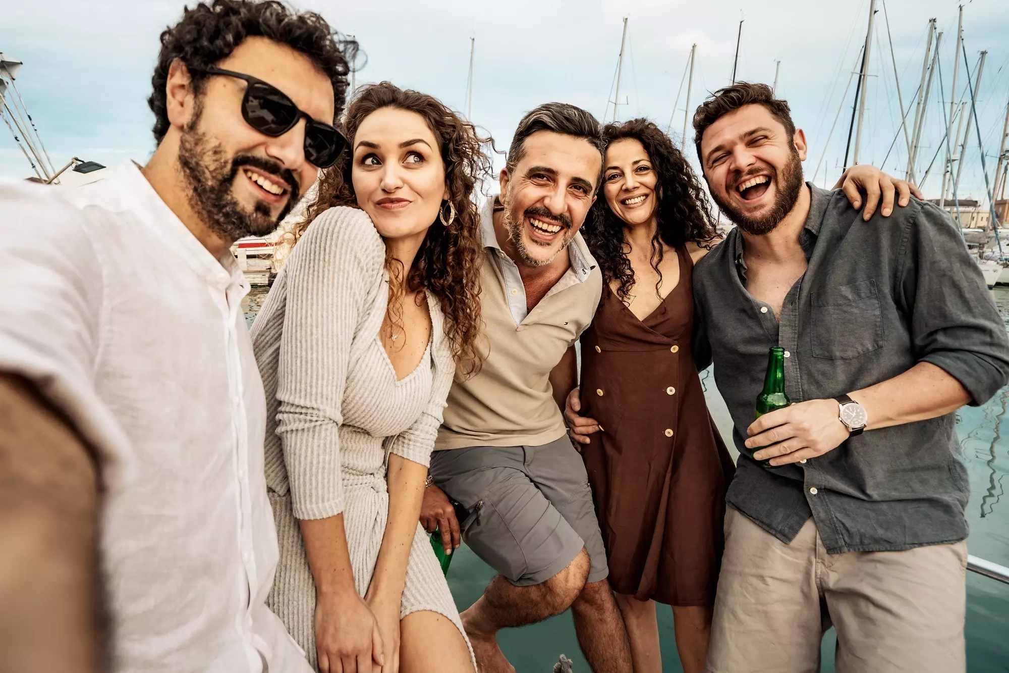 Funny group selfie of joyful friends enjoying yacht party at marina