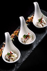 Sea bass ceviche mini portions served in beautiful Chinese spoons on a black plateau. Food concept