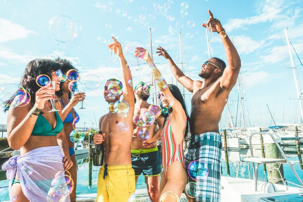 Happy friends drinking champagne in summer boat party