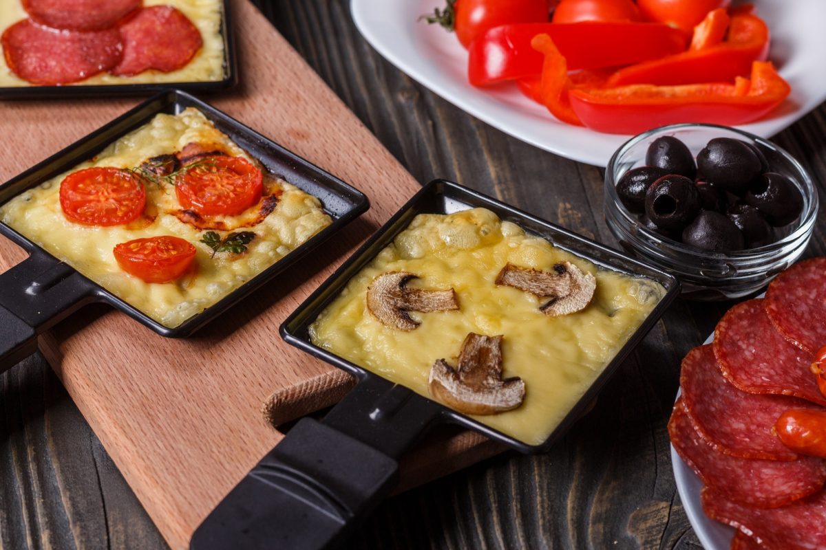 young woman is preparing a traditional Swiss cheese raclette